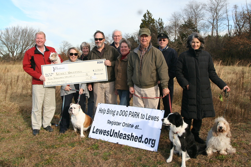 Shown at the site of the proposed dog park in Lewes are (l-r) Tom McGlone, managing partner, Heirloom Wealth Advisors holding Gracie; Lee Wiley, holding Rosebud; Bonnie Osler, Lewes City councilwoman; Larry Wiley, Lewes Unleashed board chairman; Victor Letenoff, Lewes City councilman; Jayne Abercrombie, Lewes Unleashed treasurer; Taylor Abercrombie, Lewes Unleashed secretary, holding Ghillie; Fred Beaufait, Lewes City councilman; and Linda Palmer, vice president, holding PB. BY HENRY J. EVANS JR.